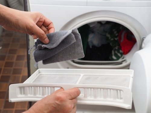 Cleaning out a dusty filter from a tumble dryer.